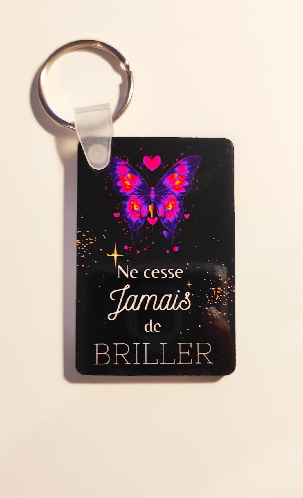 Porte-clés représentant un design personnalisé avec une phrase et un papillon multicolore
